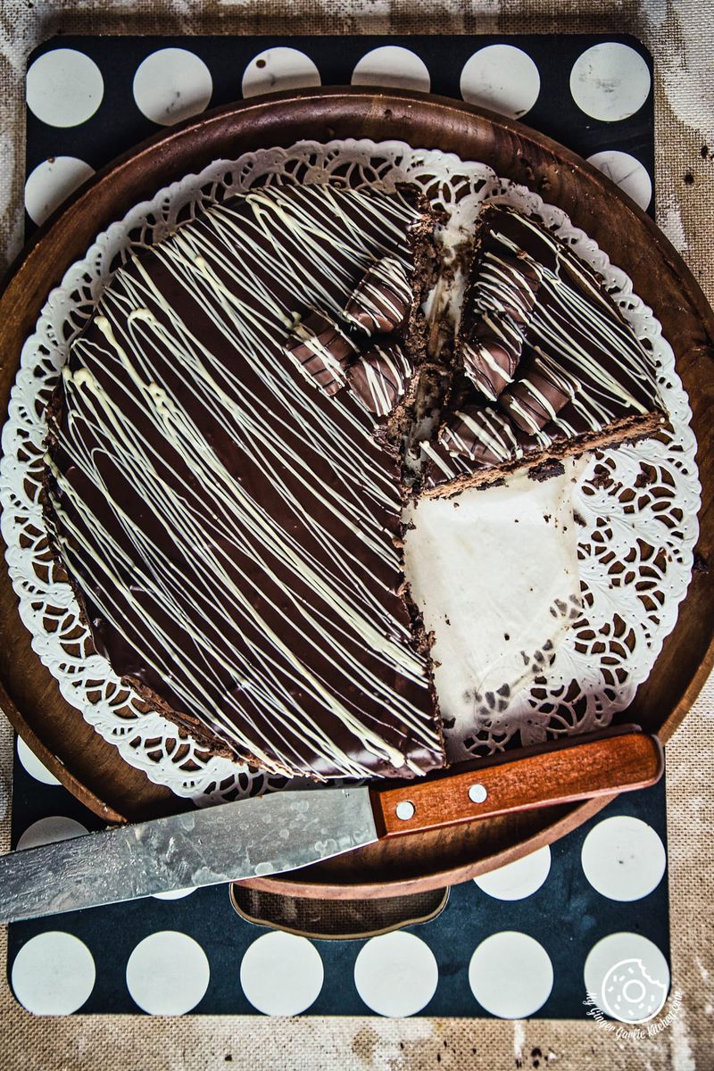 a chocolate cheesecake with white frosting and a knife on a plate