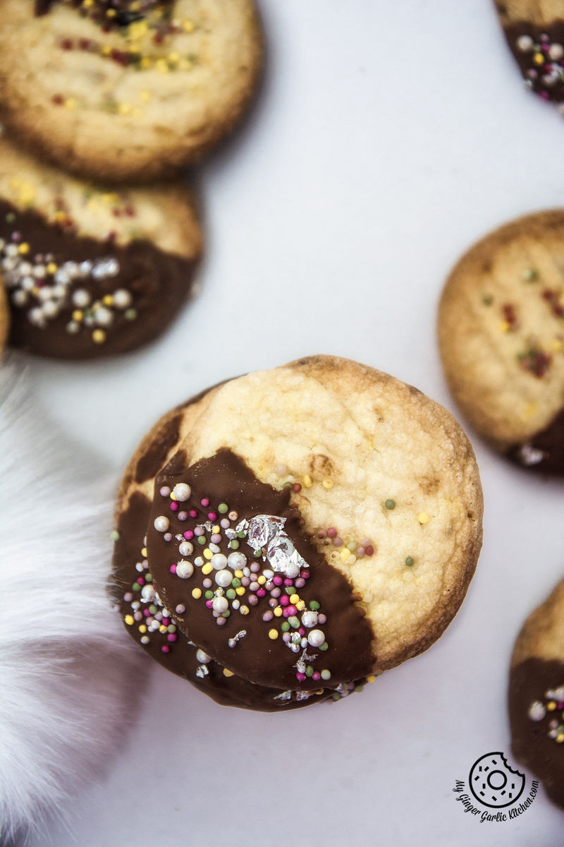 a lot of chocolate dipped whipped shortbread cranberry cookies sitting on a table