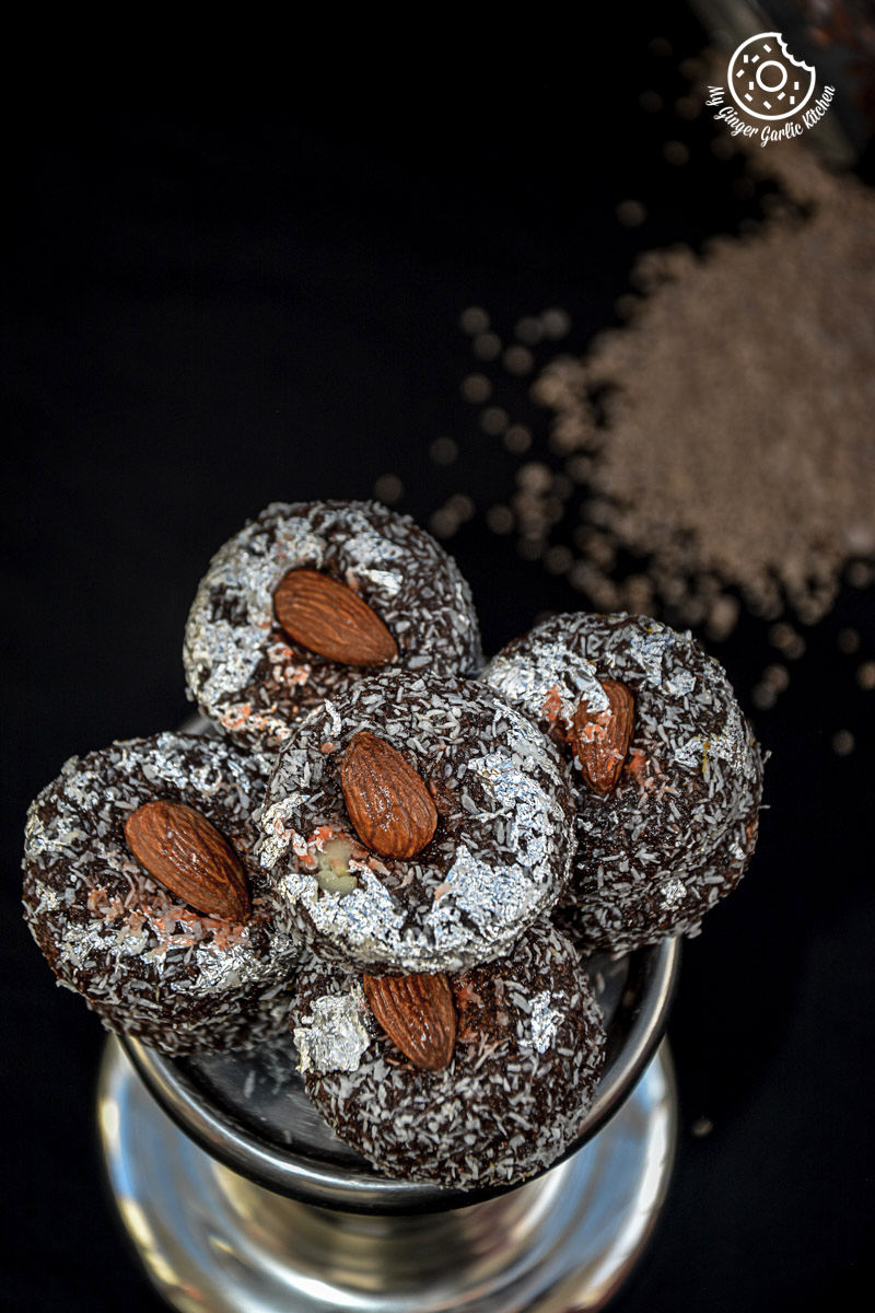 a stack of chocolate coconut delights topped with almonds in a silver bowl