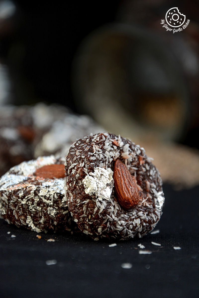 are two chocolate coconut delights topped with almonds on a black table