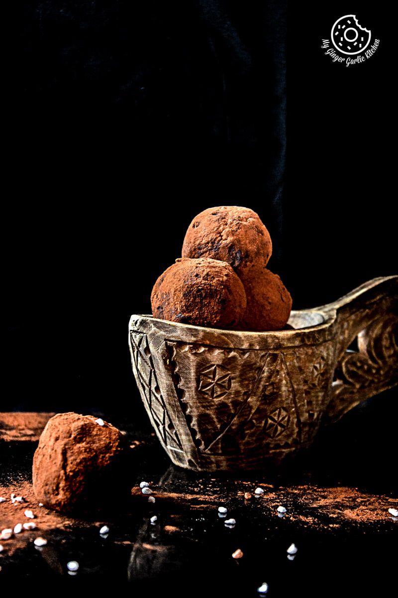 three balls of coconut milk peanut butter truffles in a bowl on a table