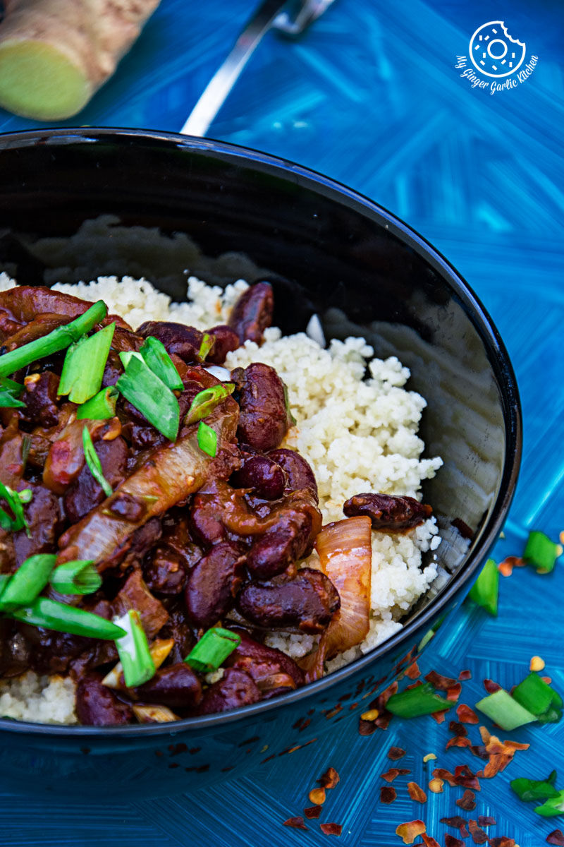 a bowl of couscous with sauteed mushrooms and kidney beans topped with spring onion greens