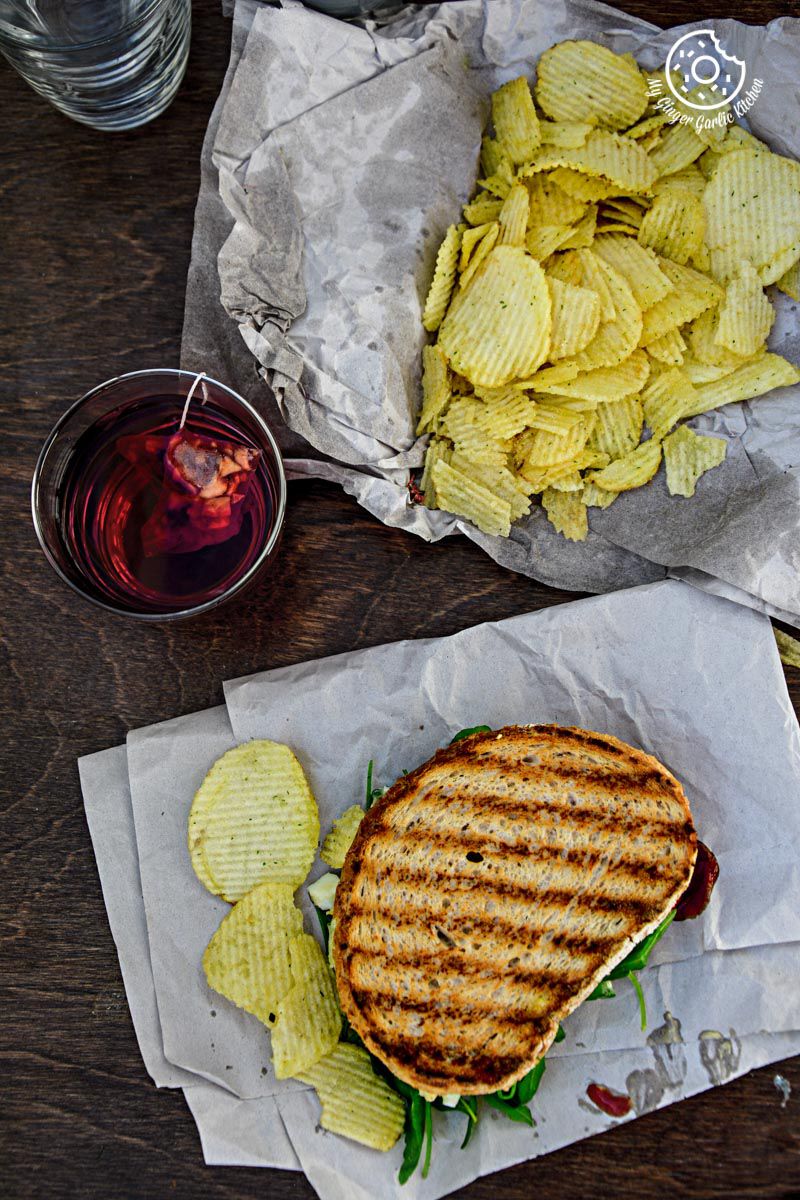 curried egg salad sandwich and chips on the table with a glass of wine