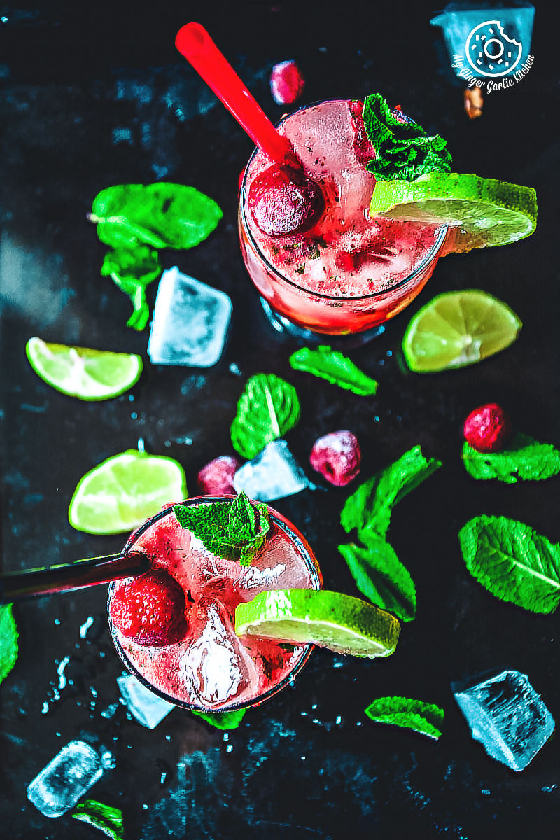 there are two glasses of dark rum strawberry mango mojito topped with mint and ice on a table