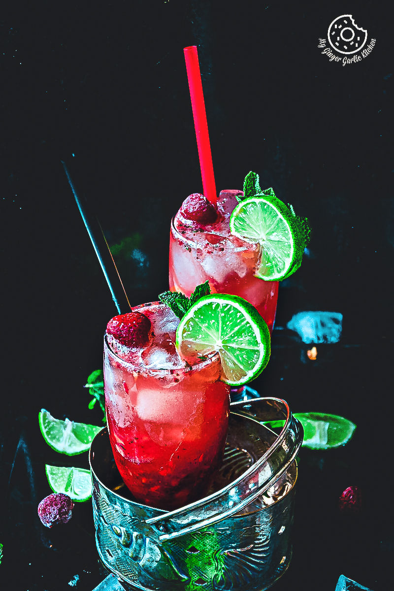 there are two glasses of dark rum strawberry mango mojito with lime slices and strawberries
