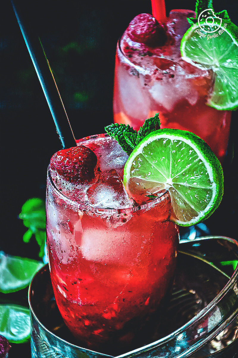 there are two glasses of dark rum strawberry mango mojito with lime and strawberries