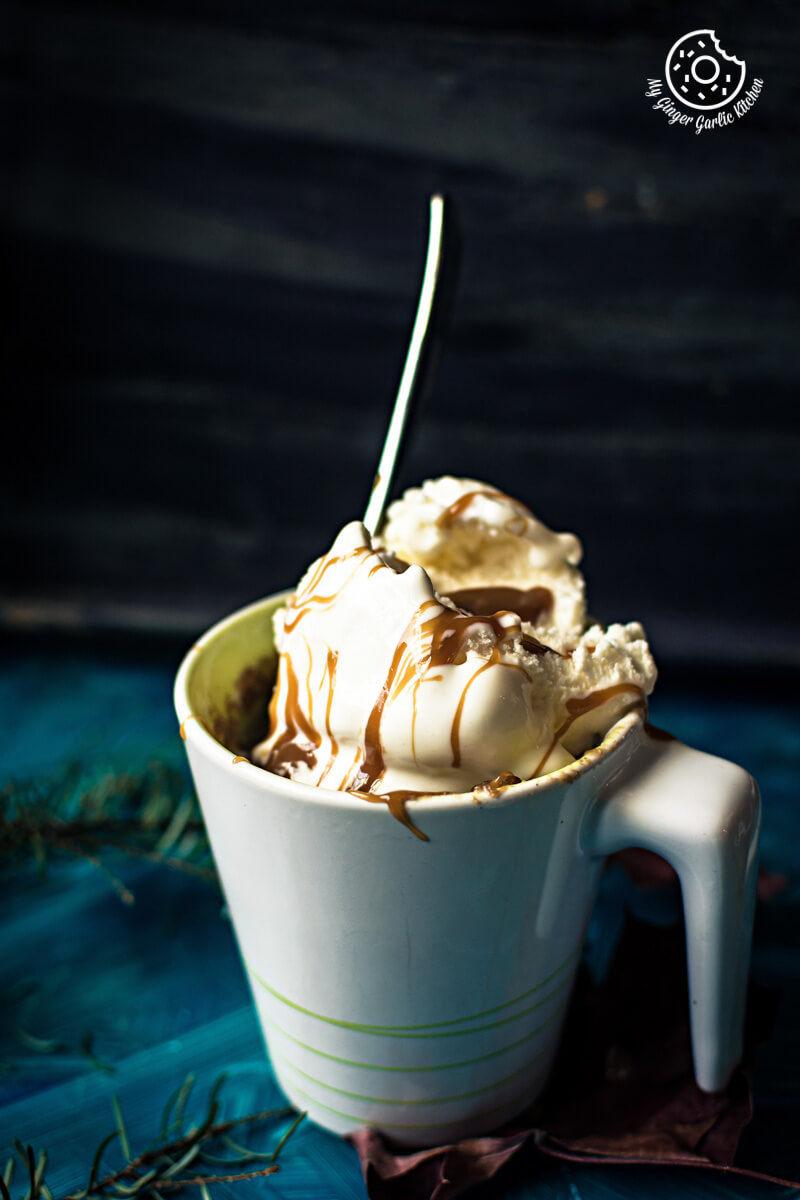 two cups of eggless apple pie mug cake with ice cream and caramel with a spoon in it