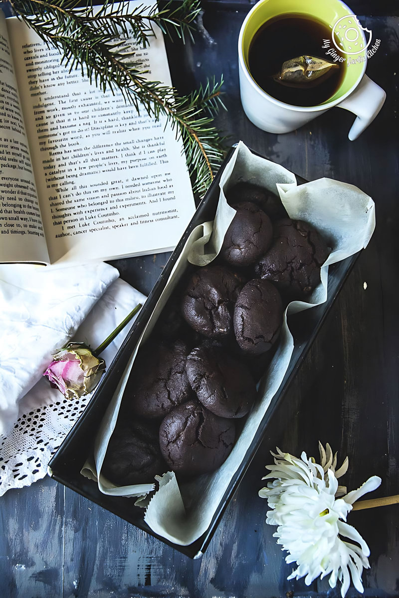a tray of eggless triple chocolate cookies and a cup of coffee on a table