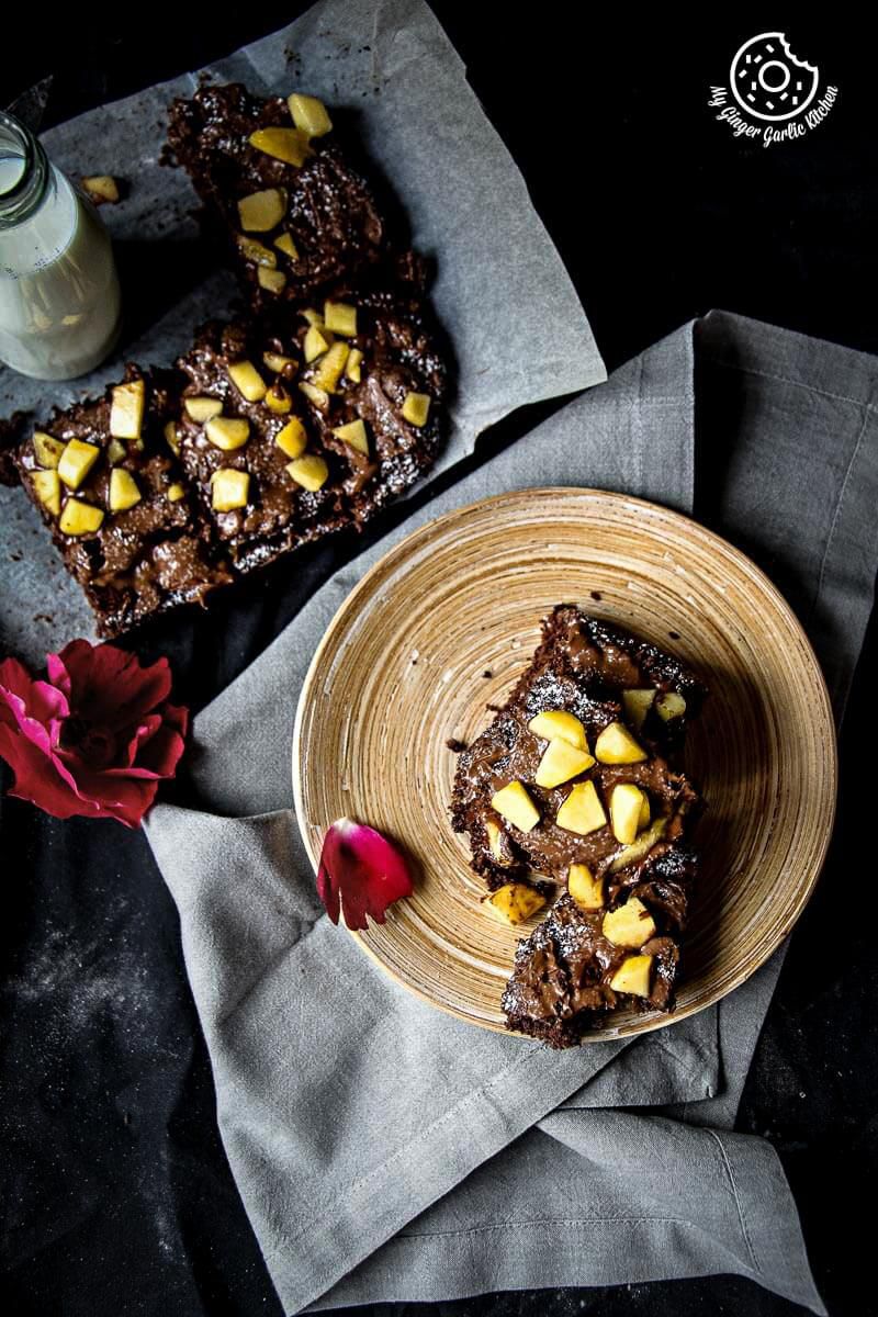 a plate of eggless peach brownies with peaches and icing sugar on top 