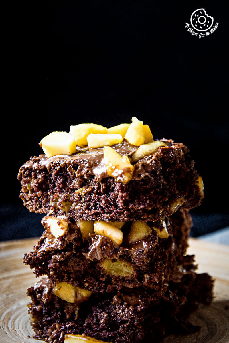 three pieces of eggless peach brownies with peaches stacked on top of each other