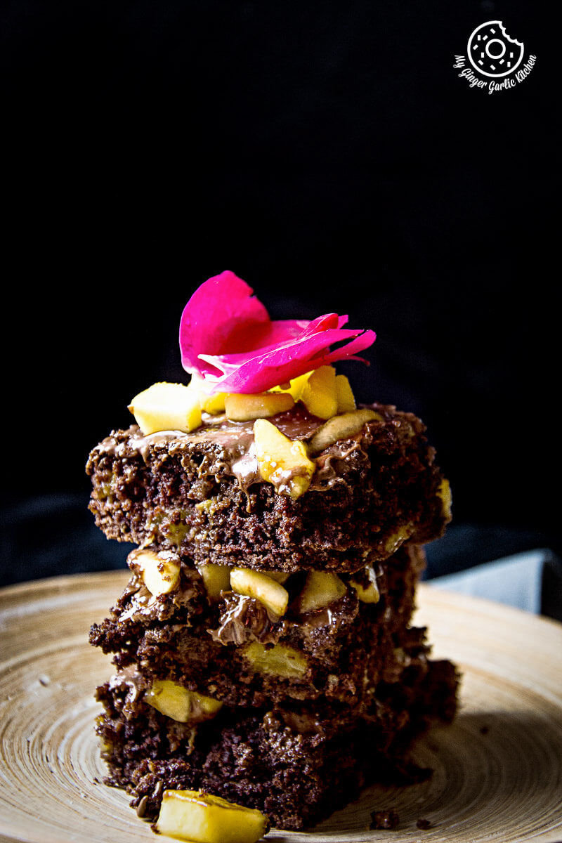 a stack of three eggless peach brownies with peaches and a flower on top