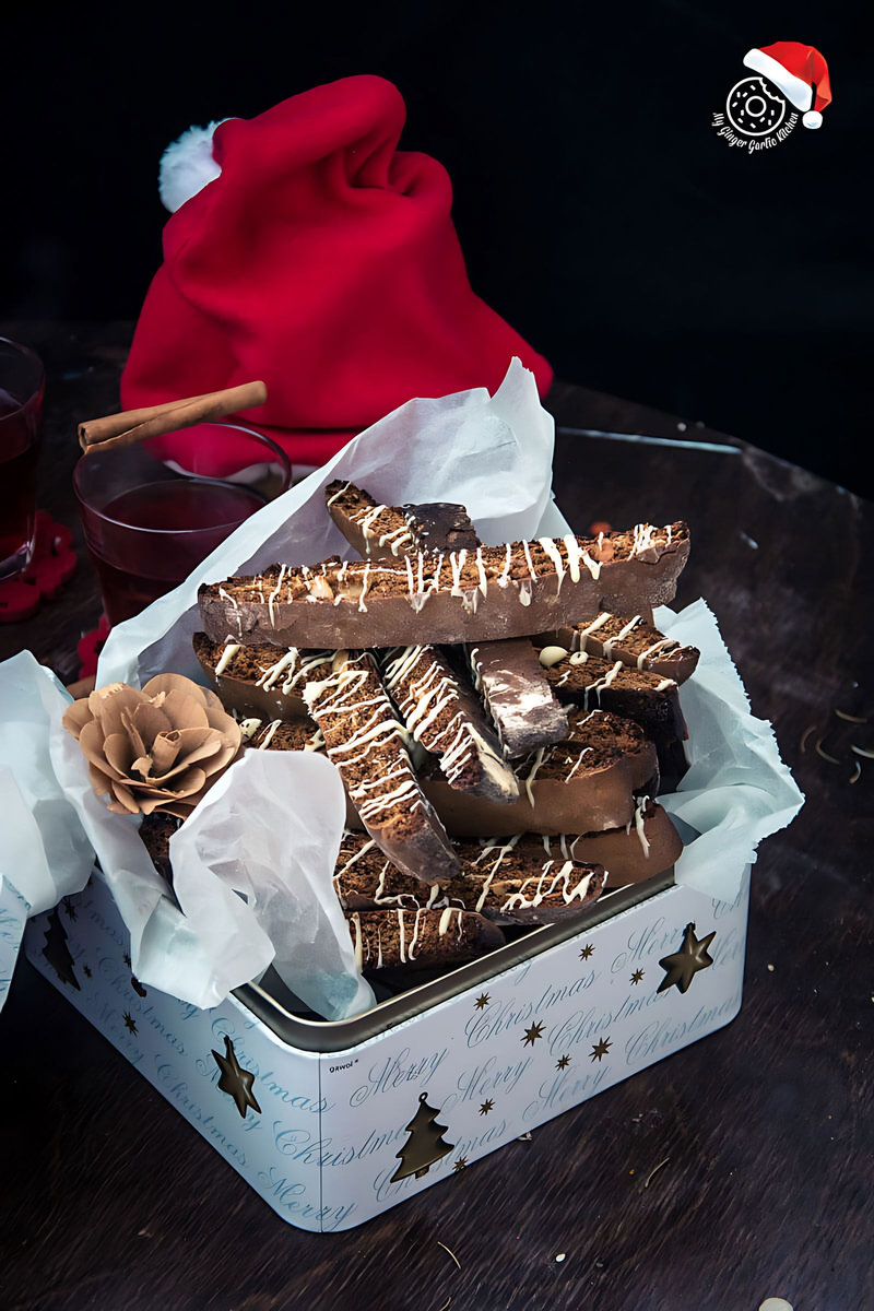 there is a box of gingerbread biscotti with white chocolate drizzle on a table with a santa hat