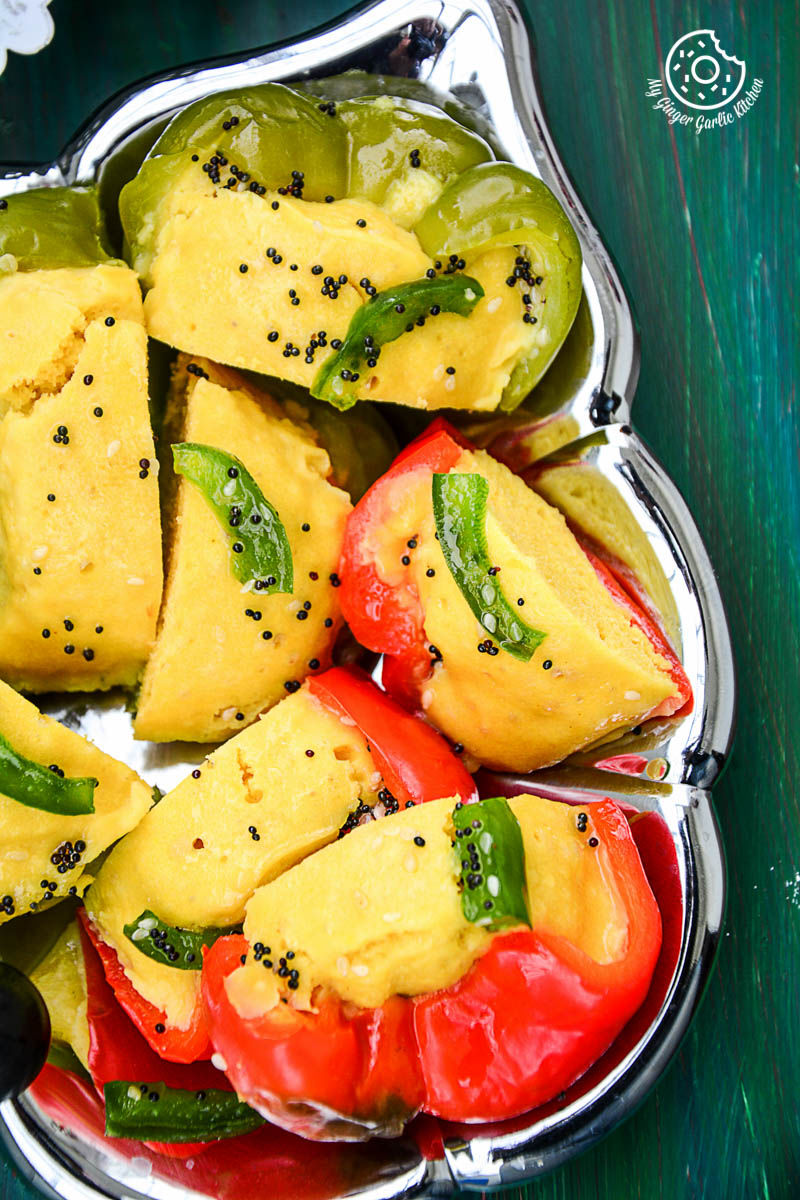 a silver tray with bell peppers filled with gujarati khaman dhokla