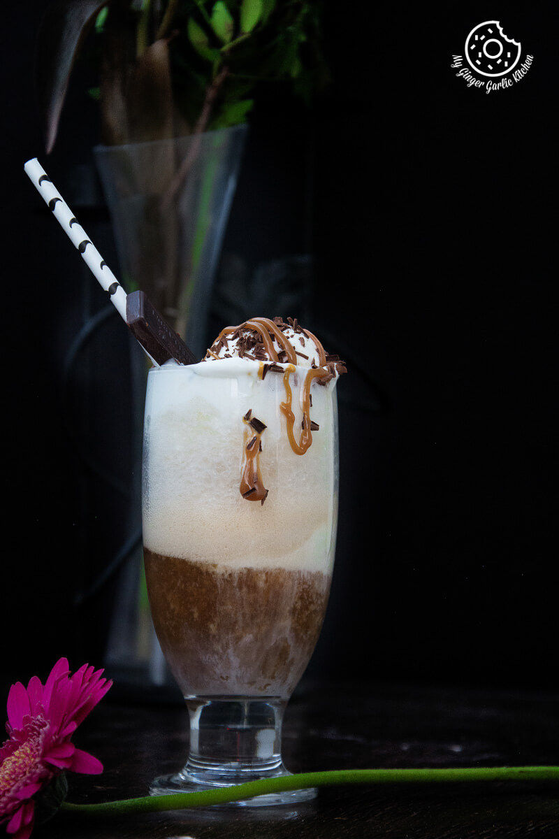 a glass of adult beer float with ice cream, chocolate sprinkles, and caramel on top