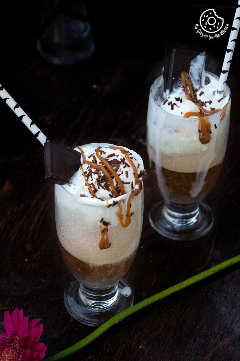 two glasses of adult beer float with ice cream, chocolate sprinkles, and caramel on top