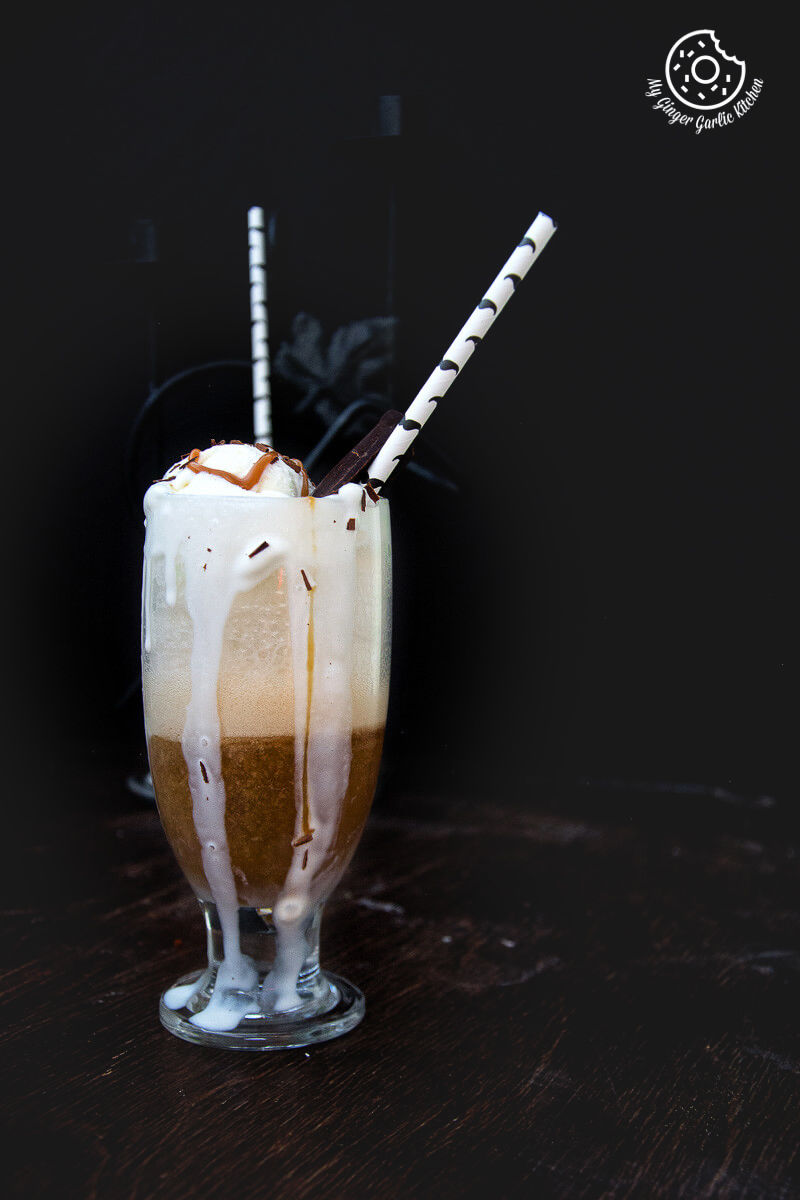 a glass of adult beer float with ice cream caramel on top and a striped straws