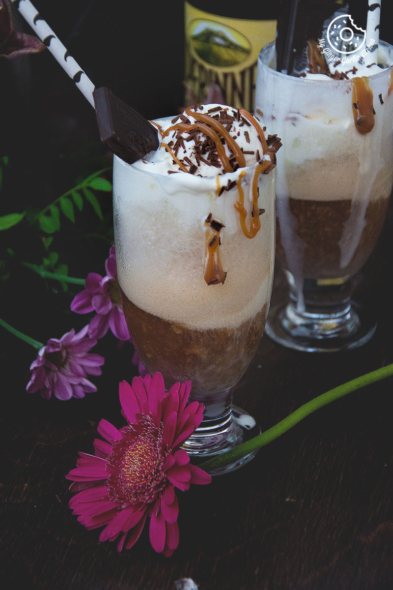 two glasses of home brewed beer float with chocolate and caramel on top and some flowers on side