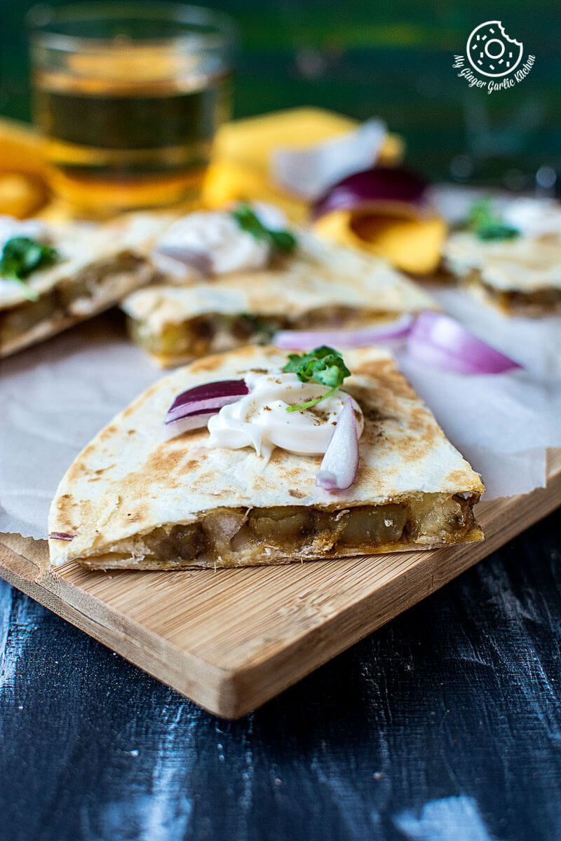 a wooden cutting board with a jeera aloo quesadilla on it