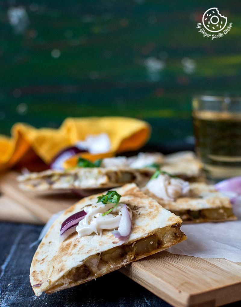 a wooden cutting board with a jeera aloo quesadilla on it