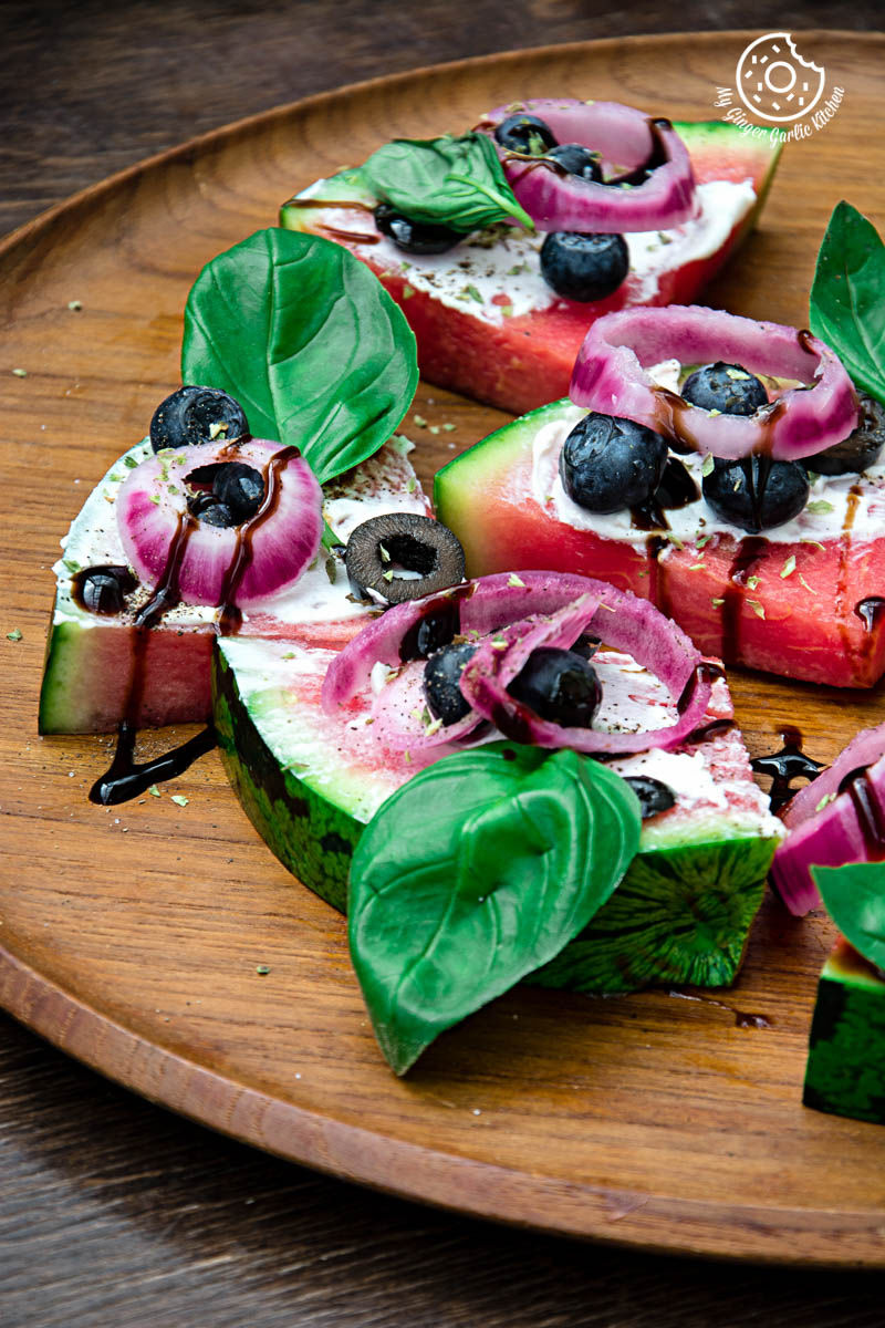 a wooden plate with slices of juicy watermelon pizza bites