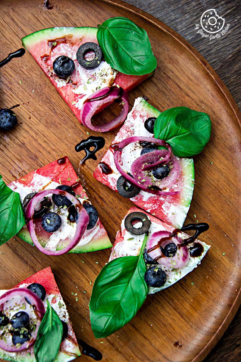 a few juicy watermelon pizza bites with olives, blueberries, and basil leaves