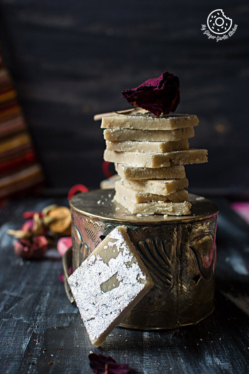 a stack of kaju kati on a table with dried rose flowers