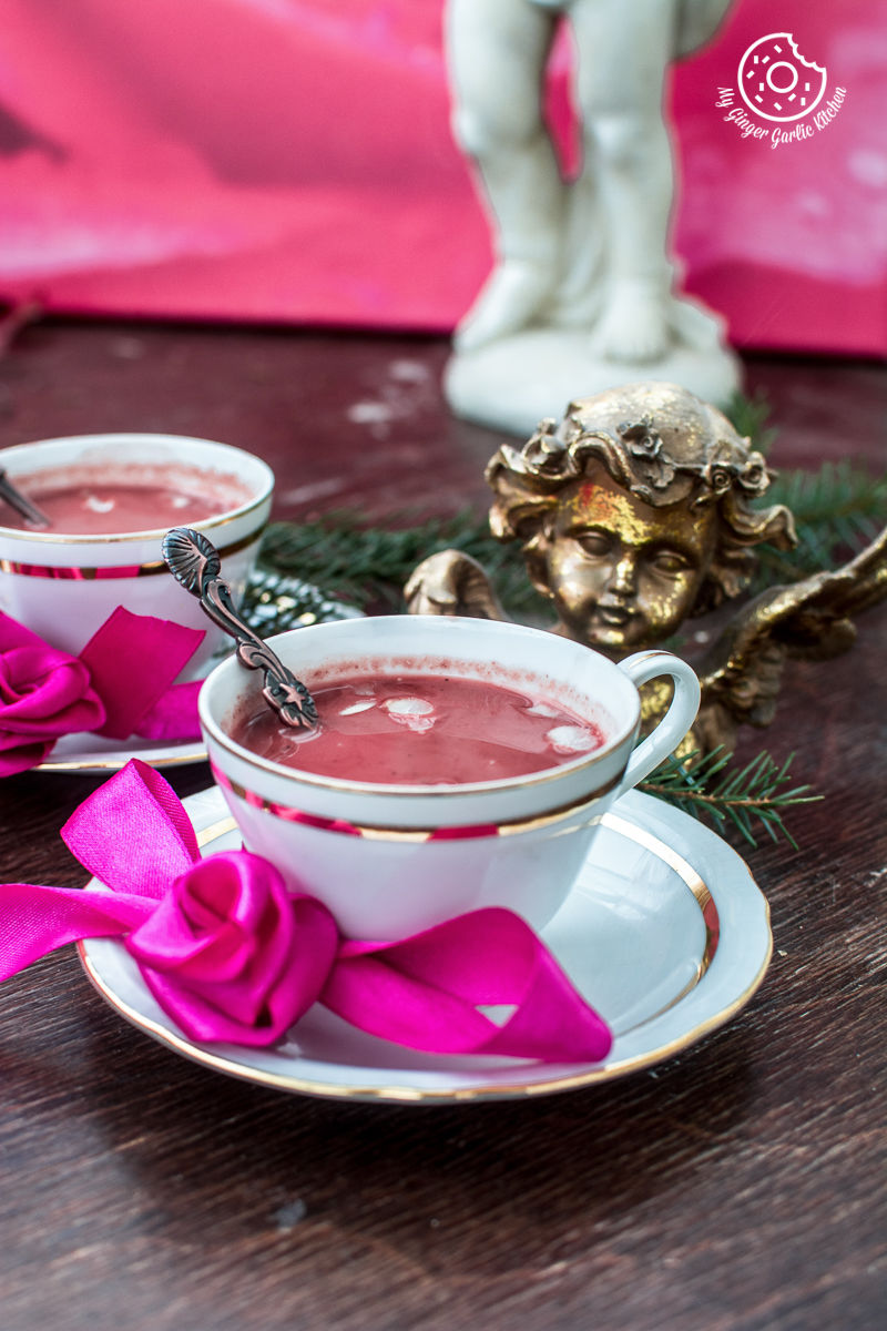 there are two cups of  kashmiri pink chai on a table with a pink bow