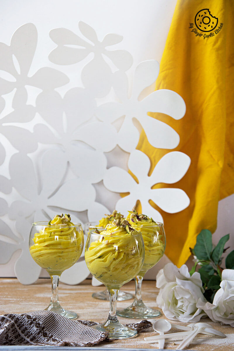 three glasses of kesar elaichi shrikhand on a table with flowers