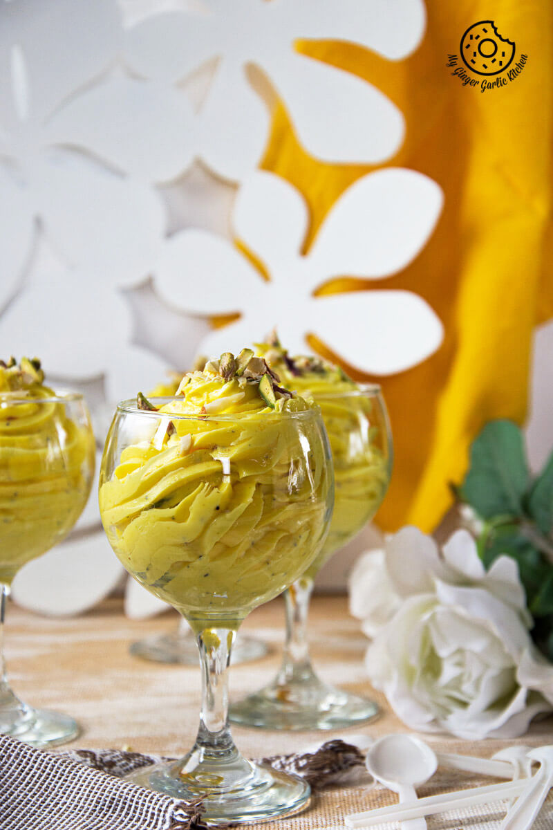 three glasses of kesar elaichi shrikhand on a table with flowers