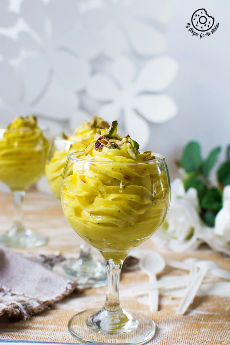 two glasses of kesar ilaichi shrikhand on a table with flowers