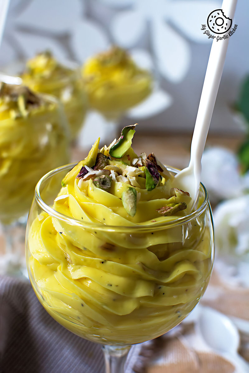 a glass of kesar ilaichi shrikhand with a spoon in it