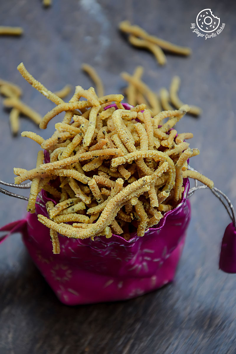 a pink bowl filled with fried lehsuni sev or garlicky chickpea noodles on a table