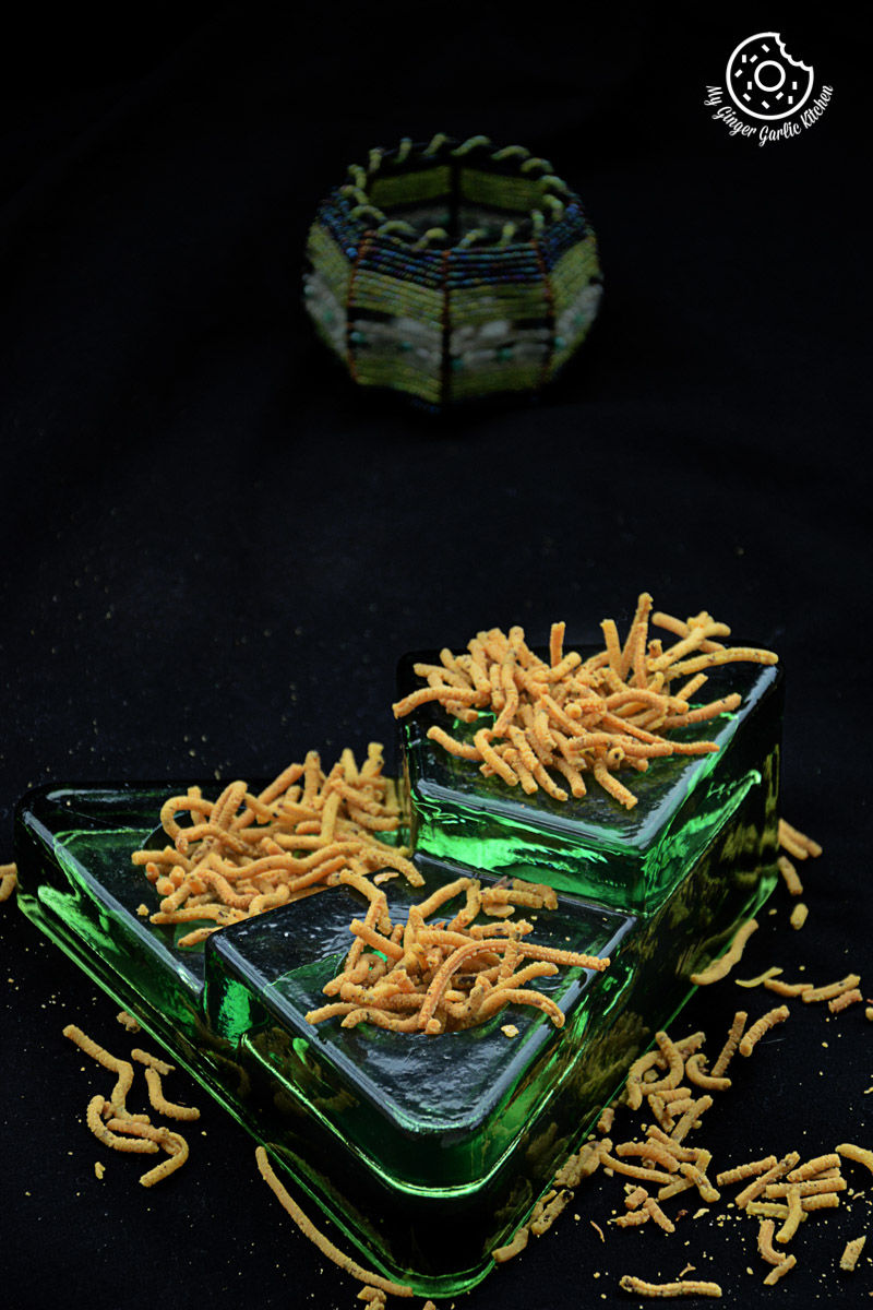 a green glass dish with some lehsuni sev or garlicky chickpea noodles on them