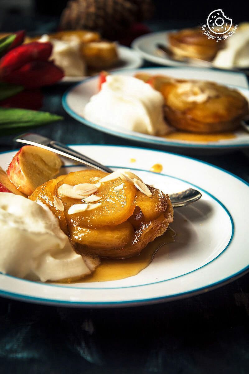 two plates of mini apple pear tarte tatin with apples and whipped cream on them