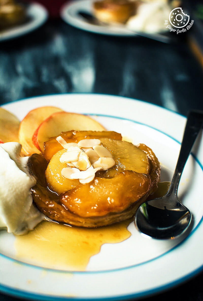 a plate of mini apple pear tarte tatin with whipped cream and a spoon on it