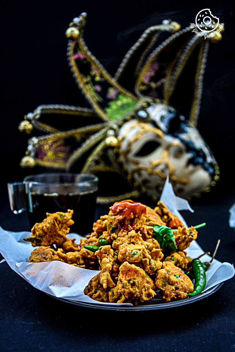 a plate of mix veg pakora with a mask on the background