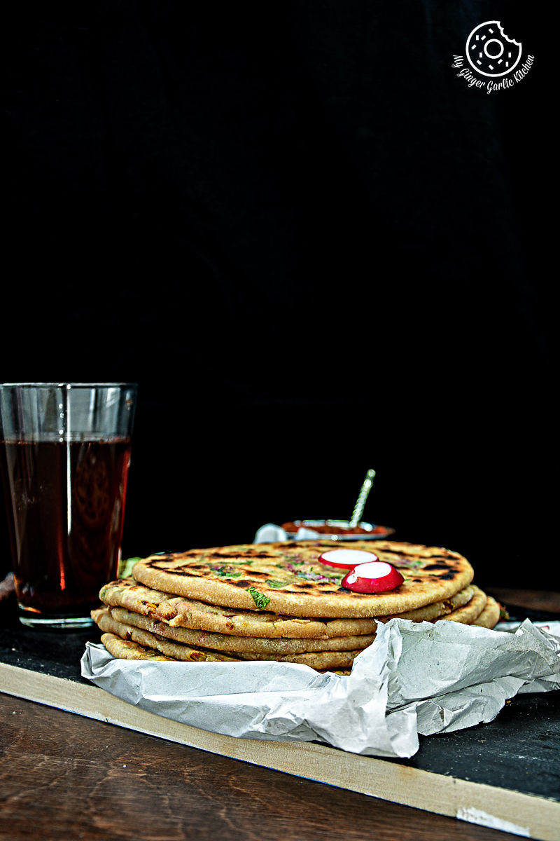 a stack of Mooli Paratha on a table with a glass of soda
