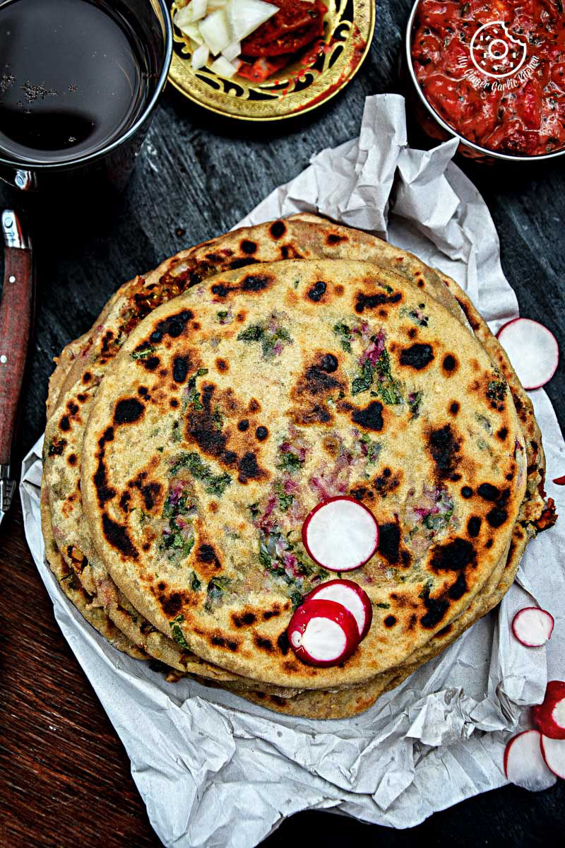 mooli paratha topped with radishes with strawberry grape chutney on a table