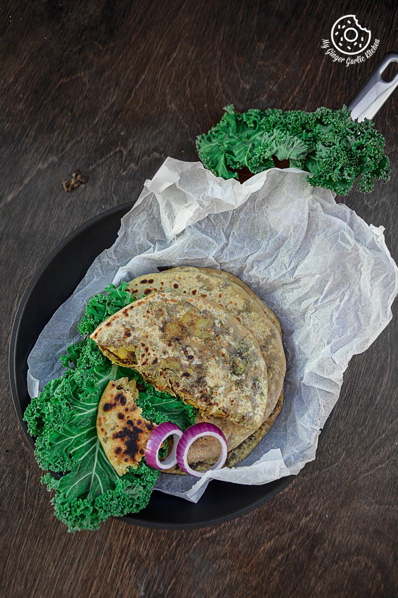 a plate of food that includes a mushroom kale stuffed parathas and kale leaves