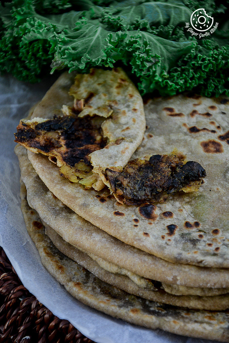 a lot of mushroom kale stuffed parathas on a plate with kale on the side