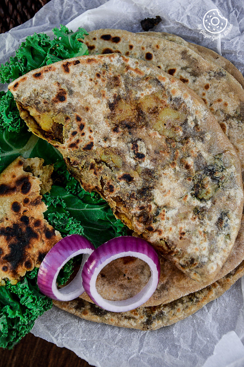 a plate of mushroom kale stuffed parathas with kale and onion slices