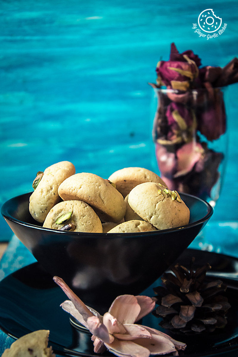 a bowl of nankhatai cookies and a glass of dried flowers