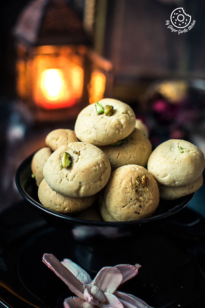 a plate of nankhatai cookies on a table with a candle
