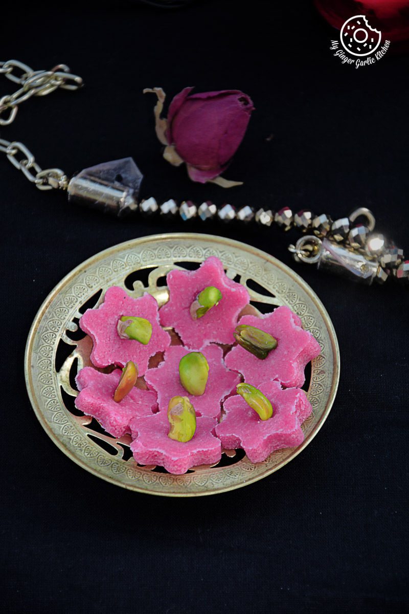 a plate of pink no bake almond flowers with pistachios on it