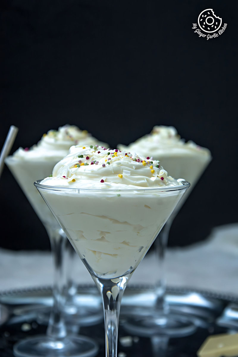 three glasses of no bake lemon cheesecake mousse with white frosting and sprinkles