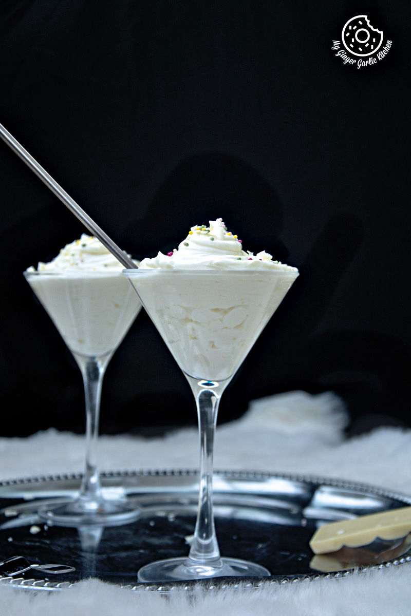 two glasses of no bake lemon cheesecake mousse on a tray with a spoon