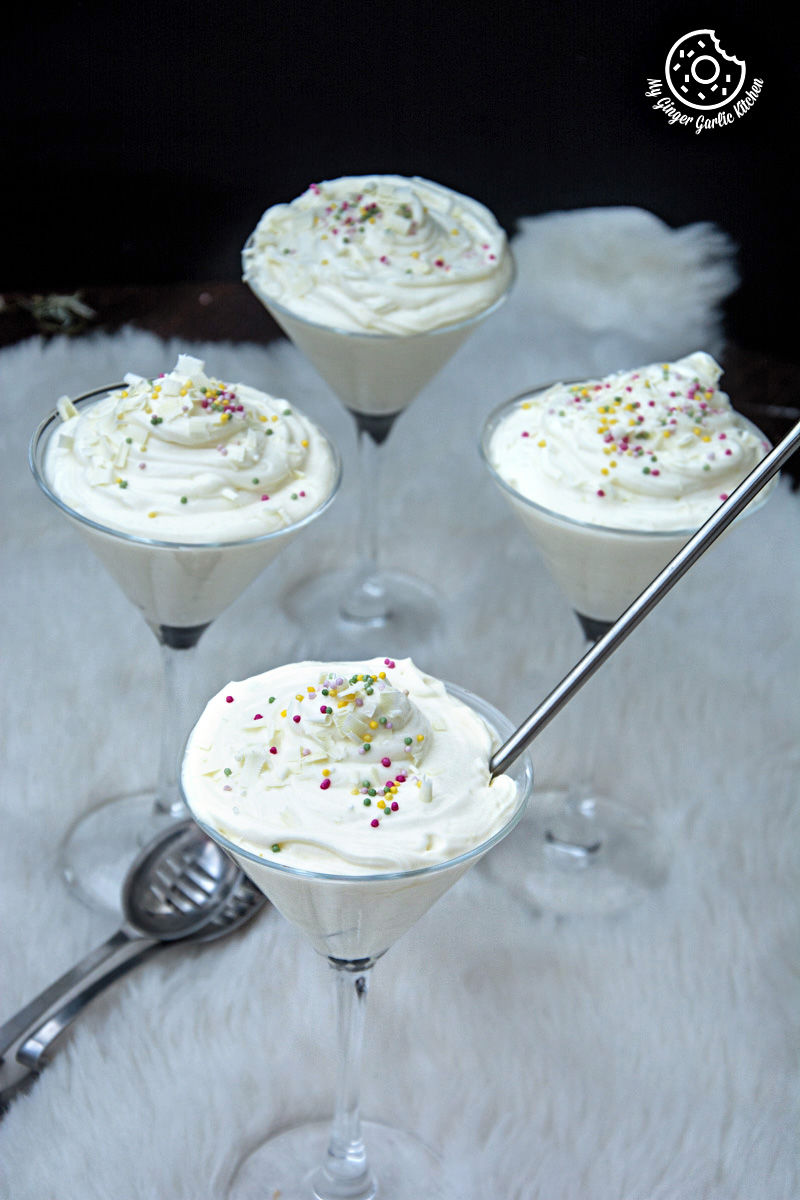 four glasses of no bake cream cheese lemon mousse with white frosting and sprinkles on a table
