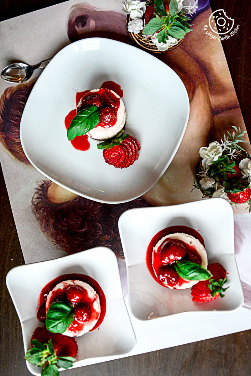 three plates with no bake mini strawberry cheesecake and strawberry compote on them on a table with a magazine