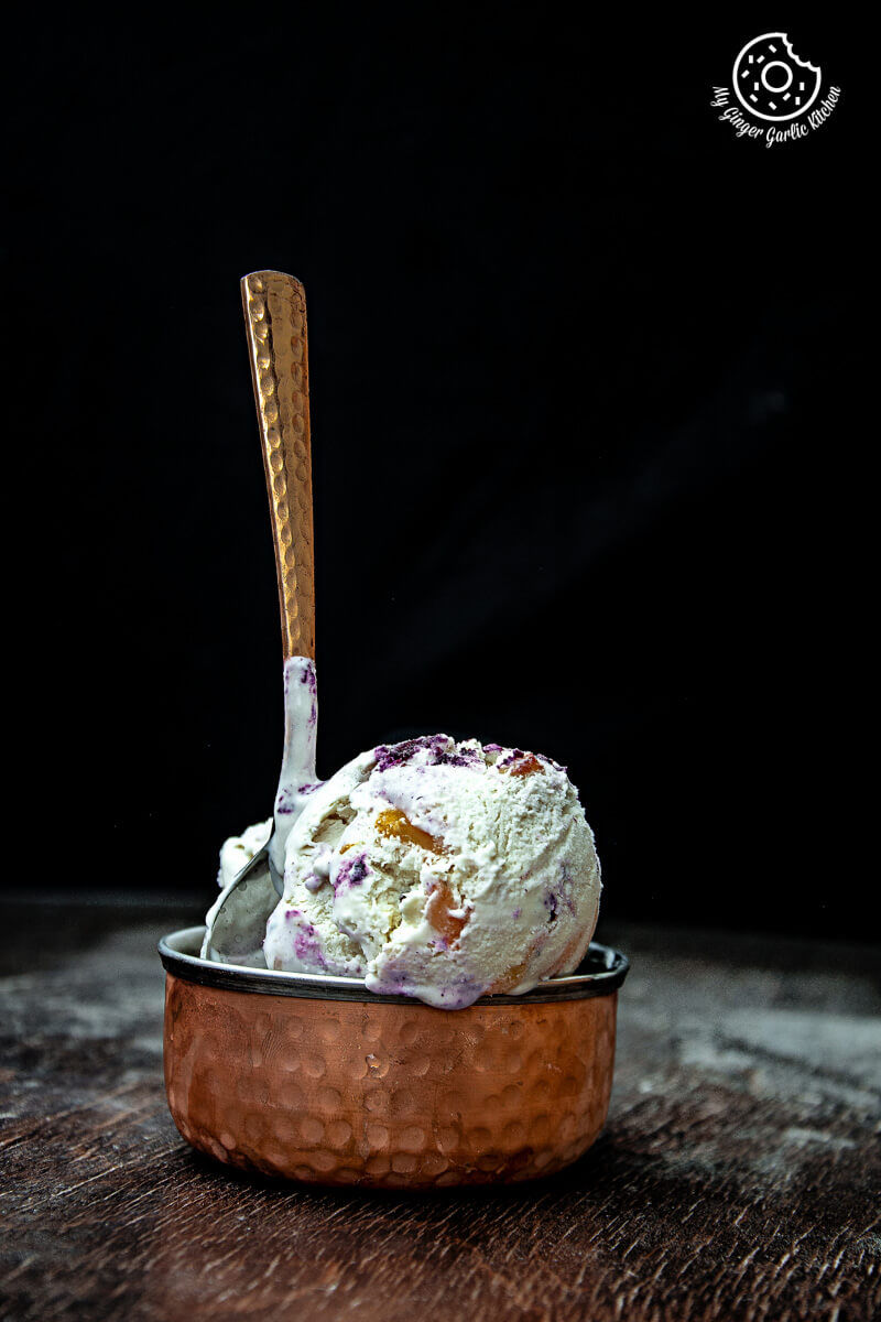 a scoop of no churn peach blueberry ice cream in a copper bowl