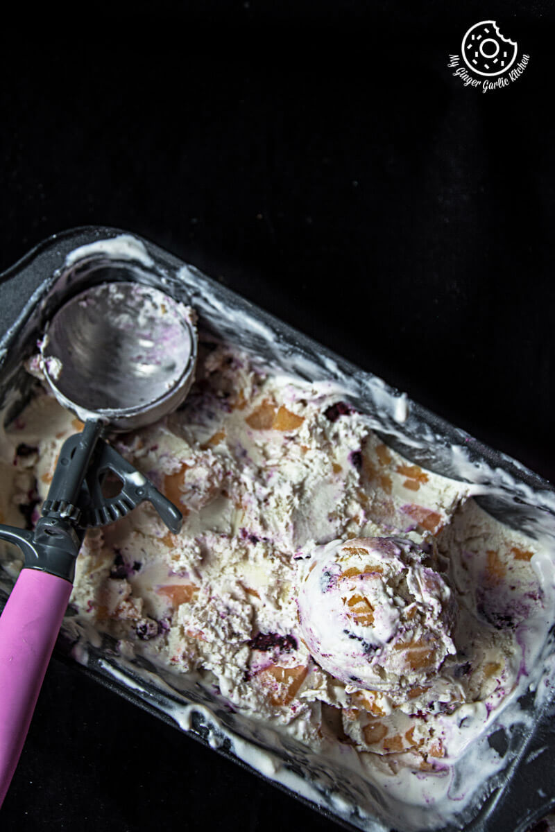 a pan of no churn peach blueberry ice cream with a scoop of ice cream